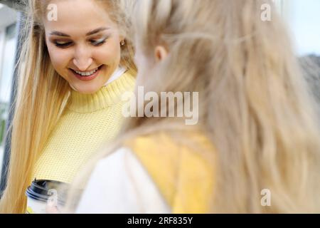 Mutter und Tochter sitzen draußen und trinken heiße Schokolade. Die Familie verbringt das Wochenende zusammen. Das Gesicht der glücklichen Mutter wurde aus der Nähe geschossen. Horizontales Foto Stockfoto