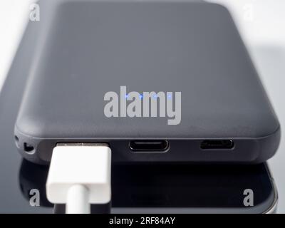 Powerbank zum Aufladen mobiler Geräte auf weißem Hintergrund. Smartphone-Ladegerät mit Netzteil. Externer Akku für mobile Geräte. Stockfoto