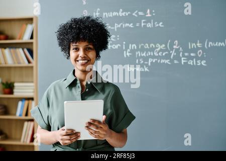 Porträt eines afroamerikanischen Lehrers, der während des Unterrichts mit einem Tablet-pc vor der Kamera lächelt Stockfoto