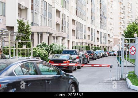 Automatisches Barrieretor, privater Parkplatz für Wohngebäude. Reihe von Autos, die im Hof geparkt sind Stockfoto