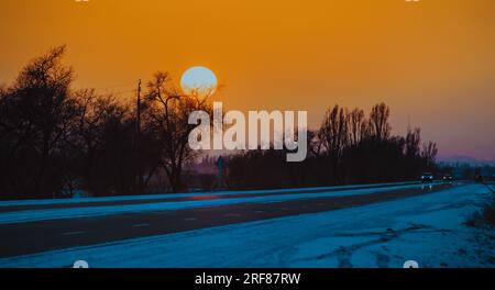 Sonnenuntergang über der Winterstraße in Kirgisistan Stockfoto