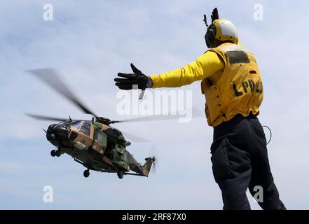 Korallenmeer, Australien. 19. November 2018. U.S. Navy Sailor Caleb Brawner, signalisiert einen Royal Australian Navy MRH-90 Taipan Helikopter, zum Start vom Cockpit der Amphibien-Transportanlage der San Antonio-Klasse USS Green Bay während des Cross-Deck-Flugbetriebs, 19. November 2018 auf der Korallensee. Kredit: MC2 Anaid Banuelos Rodriguez/US Navy Photo/Alamy Live News Stockfoto