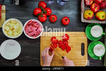 Frau kocht in der Küche, geschnittene Zutaten und Hand mit Messer Draufsicht Stockfoto
