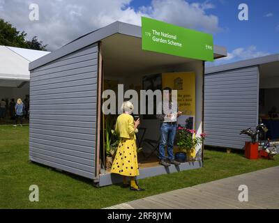 Außenfassade des Ausstellungsgeländes (NGS-Freiwillige, die auf dem Ausstellungsgelände arbeiten, um Aufmerksamkeit zu erregen) – RHS Flower Show Tatton Park, Cheshire England, Großbritannien. Stockfoto