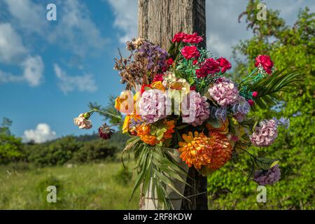 Holzkreuz mit bunten Stoffblumen an einer Kreuzung Stockfoto