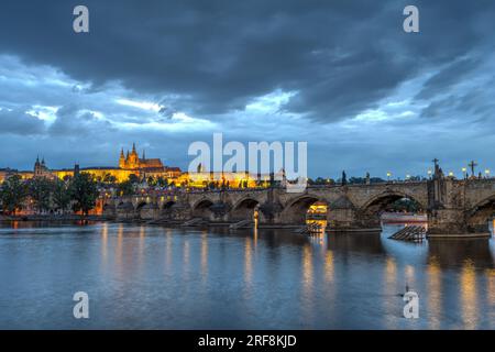 Die Burg und die berühmte Karlsbrücke in Prag in der Abenddämmerung mit dunklen Wolken am Himmel Stockfoto