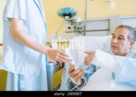 Männlicher Patient nach Verletzung oder Operation auf der Krankenhausstation Stockfoto