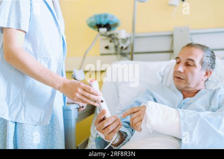 Männlicher Patient nach Verletzung oder Operation auf der Krankenhausstation Stockfoto