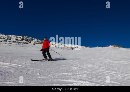 Falcade, Italien - 15. Februar 2023: Skipiste mit Skifahrer unter blauem Himmel. Die Leute fahren die schneebedeckten Berge auf Skiern hinunter. Eine Gruppe von Skifahrern auf einer Skipiste Stockfoto