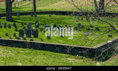 Ein Blick auf die Drohne auf einen kleinen Friedhof auf dem Land, mit einer Steinmauer umgeben, an einem sonnigen Frühlingstag Stockfoto