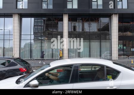 Ein Gebäude in der Cathedral Street, Glasgow, Schottland. Die Fenster spiegeln die Abbrucharbeiten hinter dem Fotografen wider, an denen viele Autos vorbeifahren. Stockfoto