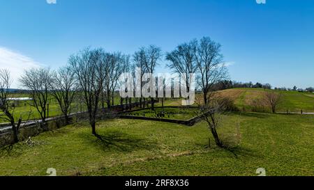 Ein Blick auf die Drohne auf einen kleinen Friedhof auf dem Land, neben einem vorbeifahrenden Dampflok, an einem sonnigen Frühlingstag Stockfoto