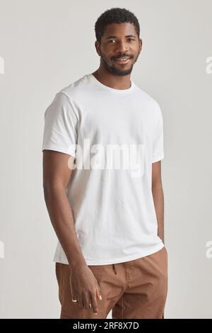 Minimales Porträt eines gutaussehenden schwarzen Mannes, der im Studio vor weißem Hintergrund posiert und ein weißes Hemd trägt Stockfoto