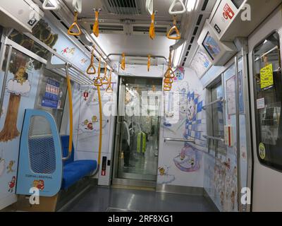 Blick auf das Innere eines leeren Wagens im U-Bahn-System von Tokio, mit blauen Sitzen und gelben Haltegriffen für alle Stehenden. Stockfoto