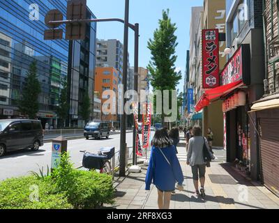 Modernes Japan: Blick auf eine Straßenszene in der Metropole Tokio mit hohen Gebäuden und Fußgängern auf dem Bürgersteig. Stockfoto