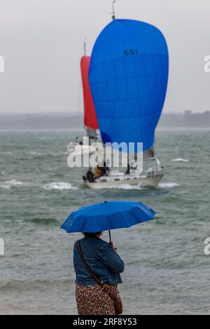 frau mit Schirm im portierenden Regen, die die Yachtrennen bei der jährlichen cowes Week Regatta im august auf der Insel wight beobachtet. cowes Week Regatta Stockfoto