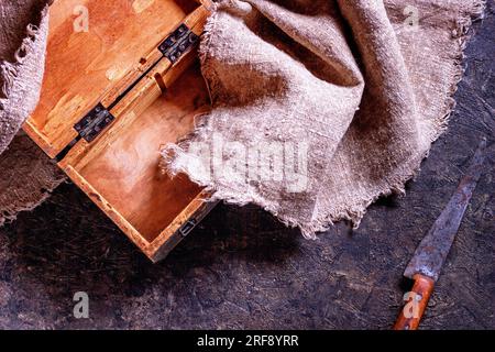 Vintage Metzgermesser und alte Holzkiste auf Steinküchenoberfläche. Draufsicht mit selektivem Fokus Stockfoto