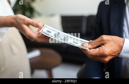 Ein weißer alter Geschäftsmann im Anzug gibt einer Frau Bargeld, Hand in Büroeinrichtung, Nahaufnahme Stockfoto