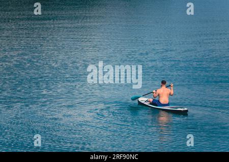 Ein Mann auf dem Paddleboard in der Mitte des Seefeldes Stockfoto