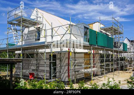 Ein unvollendetes modernes Einfamilienhaus, umgeben von Gerüsten, blauer Himmel Hintergrund, Wohnhaus im Bau Stockfoto