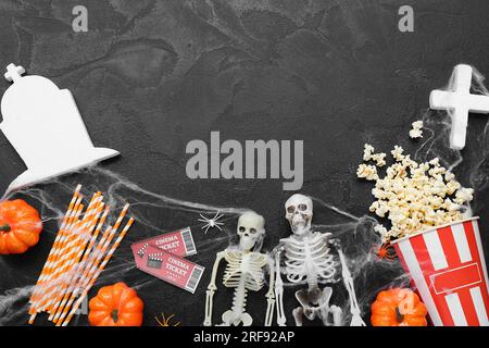 Komposition mit leckerem Popcorn, Skeletten und Kinokarten auf dunklem Hintergrund. Halloween-Feier Stockfoto