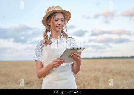 Frau Landwirt Strohhut intelligente Landwirtschaft stehende Ackerland lächeln mit digitalen Tablet Frau Agronomin spezialisierte Forschung Überwachung Analyse Daten Landwirtschaft kaukasischen Arbeiter landwirtschaftlichen Bereich Stockfoto