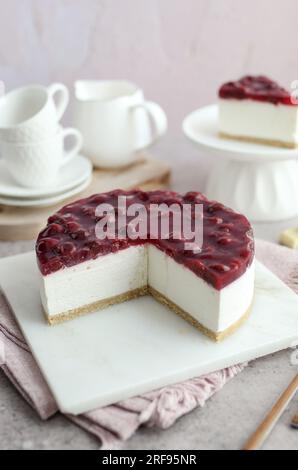 Gebackene weiße Schokolade und Kirschkäsekuchen auf einem weißen Teller. Weiße Kaffeetassen und rosafarbener Hintergrund. Stockfoto