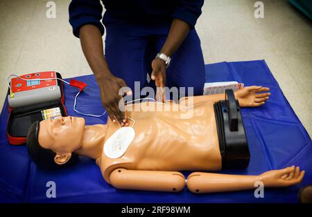 Erste-Hilfe-Training: Kurs mit Schaufensterpuppe zur Anwendung eines Defibrillators. Stockfoto