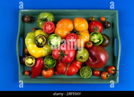 Alte Tomaten ganz und in zwei Hälften in einem grünen Tablett geschnitten. Stockfoto