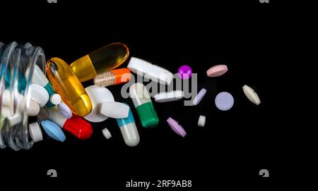 Kapseln, Tabletten und Kapseln auf schwarzem Hintergrund. Stockfoto