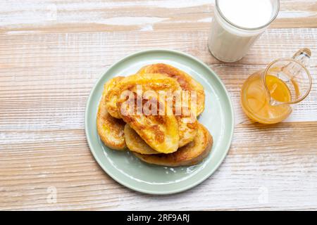 Torrijas, Französischer Toast Im Spanischen Stil Mit Orangengarnierung, Glasur, Frischen Blaubeeren, Erdbeere Auf Grünem Teller, Holztisch. Eine Hälfte Orange Stockfoto