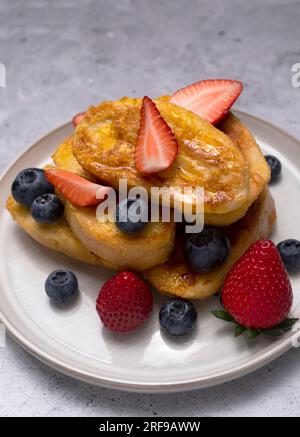 Torrijas, Französischer Toast Im Spanischen Stil Mit Orangengarnierung, Glasur, Frischen Blaubeeren, Erdbeere Auf Grünem Teller, Holztisch. Eine Hälfte Orange Stockfoto