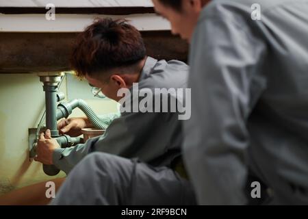 Installateure, die neue Kunststoffrohre unter dem Küchenspül installieren Stockfoto