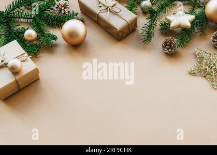 Weihnachtlicher Hintergrund mit Fichtenzweigen, Geschenkschachteln und Kugeln auf beigefarbenen Tischen. Draufsicht, flach liegend, Kopierbereich. Stockfoto