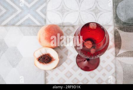 Glas mit kaltem Getränk und Pfirsichen auf Vintage-Fliesen Hintergrund. Draufsicht. Selektiver Fokus. Stockfoto