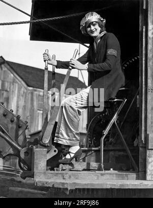 Oakland, Kalifornien: ca. 1930. Eine lächelnde Frau an der Steuerung einer Dampfschaufel. Stockfoto