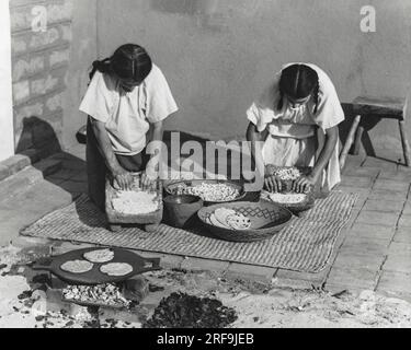 Kalifornien: ca. 1930 indianische Frauen, die Mais zu Mehl mahlen, um Tortillas bei der Mission zu machen. Stockfoto