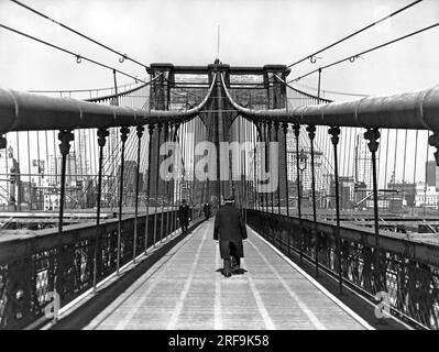New York, New York: 6. April 1938 Ein gemütlicher Spaziergang über eine der schönsten Brücken der Welt, die berühmte Brooklyn Bridge, die 1883 erbaut wurde. Stockfoto