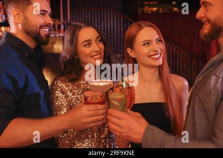 Fröhliche Freunde, die Gläser mit frischen Cocktails in der Bar trinken Stockfoto