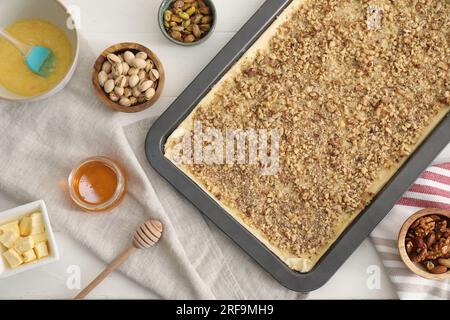 Ich mache köstliche Baklava. Backform mit Teig und Zutaten auf weißem Tisch, flach liegend Stockfoto