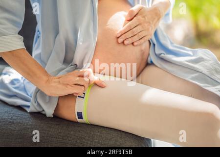 Eine zufriedene und bequeme Schwangere trägt Kompressionsstrümpfe und sorgt so für eine bessere Beingesundheit und Unterstützung während ihrer Schwangerschaft Stockfoto