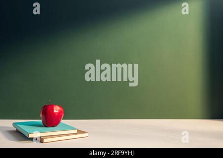 Apfel und Bücher auf dunkelgrüner Wand oder Tafel für das Bildungskonzept Stockfoto