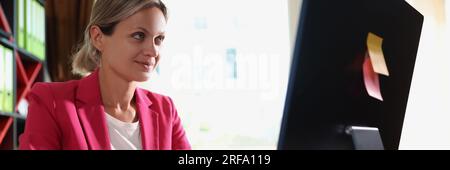 Interessierte Frau, die im Büro auf einen Computerbildschirm schaut. Stockfoto