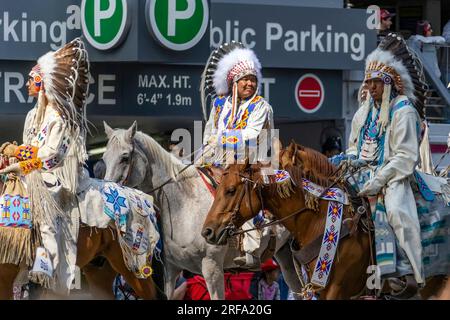 Calgary, Alberta, Kanada. 7. Juli 2023. Einige Leute der First Nations tragen traditionelle Kleidung, während sie auf Pferden auf einer öffentlichen Festumarde reiten. Stockfoto