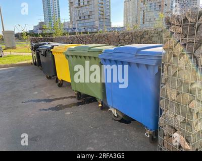 Große moderne Kunststoffbehälter aus schwarzem, gelbem, grünem und blauem Kunststoff für die getrennte Sammlung und anschließendes ökologisches Recycling von Abfällen in einem neuen Gebiet Stockfoto