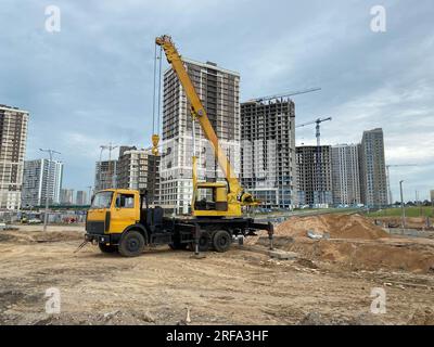 Großer gelber Mobilitätskran im modernen Industriebau, der auf einem Lkw montiert ist, wird beim Bau von neuen Wohnungen, Häusern, Gebäuden in einem großen C verwendet Stockfoto