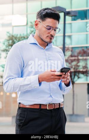 Vertikales Porträt eines ernsthaften Geschäftsmanns, Verkäufers, Managers oder Maklers, der ein ernsthaftes Gespräch über sein Mobiltelefon führt oder SMS liest. Geschäftsmann, der mit dem Handy im Internet surft. Hochwertiges Foto Stockfoto