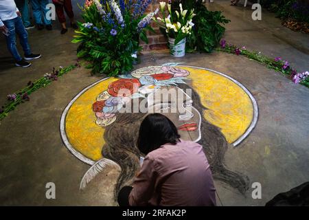 Medellin, Kolumbien. 31. Juli 2023. Ein Künstler malt ein Porträt mit Kreide, während das ikonische Vasquez-Gebäude gefüllt ist mit Blumen für die „Feria de las Flores“ in Medellin, Kolumbien, 31. Juli 2023. Foto: Jessica Patino/Long Visual Press Credit: Long Visual Press/Alamy Live News Stockfoto