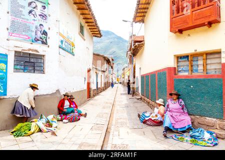 Eine peruanische Frau, die auf dem Boden sitzt und Sachen in Pisac, Heiliges Tal, Peru verkauft Stockfoto