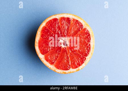 Nahaufnahme der Hälfte der roten Grapefruit und Kopierbereich auf blauem Hintergrund Stockfoto